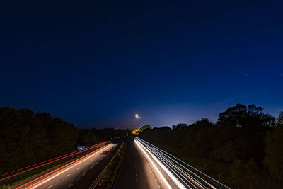 Light trails on highway against sky at night