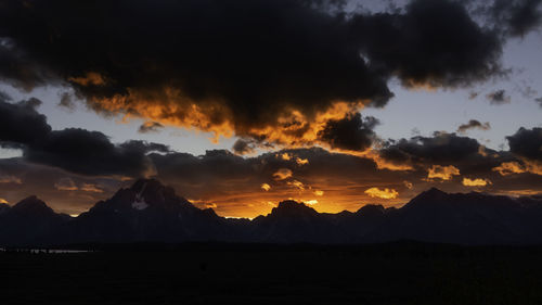 Scenic view of silhouette mountains against storm clouds