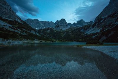 Scenic view of lake by mountains against sky