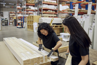 Multiracial female coworkers arranging planks in lumber industry