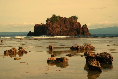 Scenic view of beach by rock formations against sky