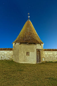 Building on field against clear blue sky