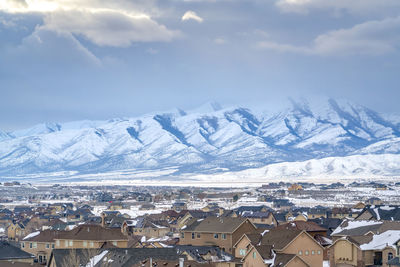 Aerial view of townscape and snowcapped mountains against sky