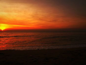 Scenic view of sea against dramatic sky during sunset