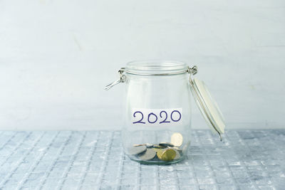 Close-up of glass jar on table against wall