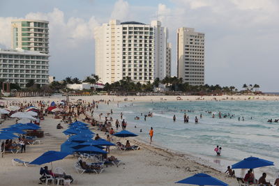 People on beach against buildings in city