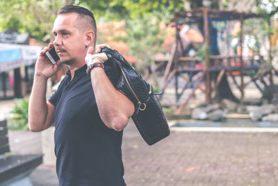 Man holding mobile phone in city