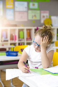 Girl writing in paper at kindergarten