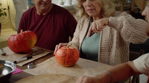 Midsection of woman holding pumpkin on table