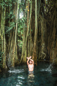 Young man in tree trunk in forest