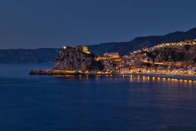 Scenic view of sea by buildings against clear blue sky