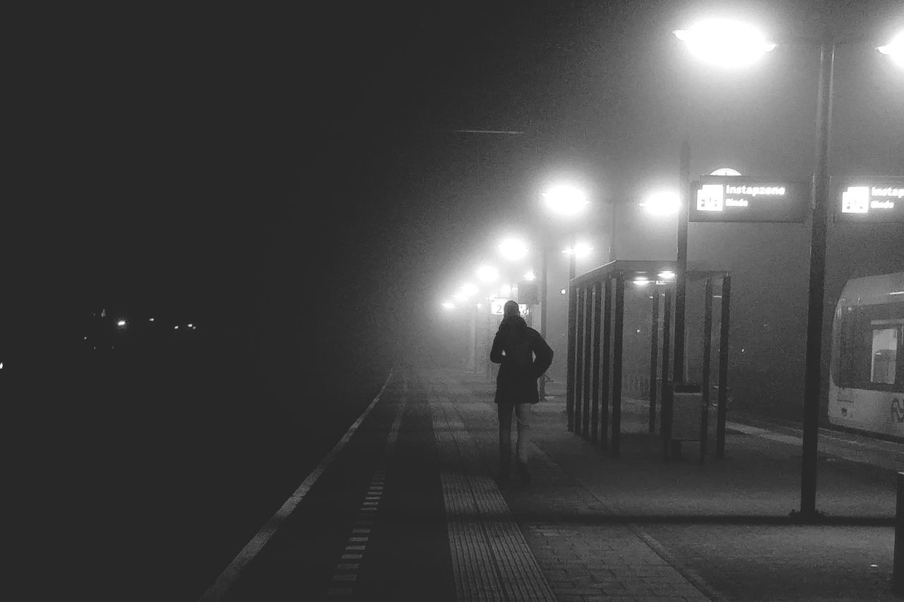 MAN WALKING ON ILLUMINATED STREET LIGHTS AT NIGHT DURING RAINY SEASON