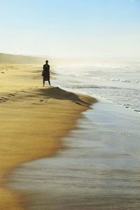 Man walking on beach against clear sky