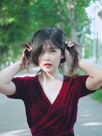 Portrait of beautiful woman holding hair while standing outdoors