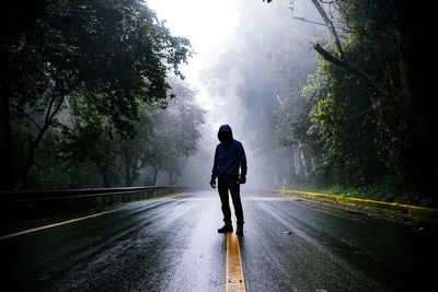A man standing on empty road during foggy weather
