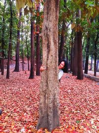 Woman with leaves amidst trees during autumn