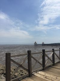 Pier on sea against cloudy sky