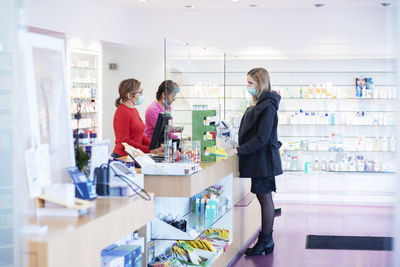 Pharmacist talking with customer at checkout counter of pharmacy store