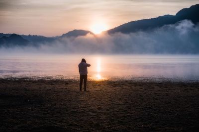 Man standing on beach against sky during sunset