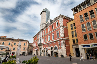 People on street amidst buildings in city against sky