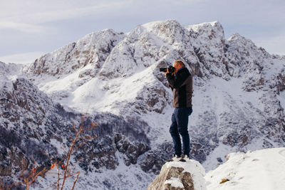 Rear view of man standing on snow covered mountain