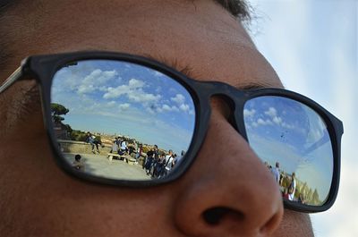 Reflection of man on sunglasses against sky