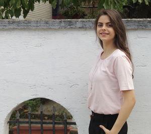 Portrait of smiling young woman standing against built structure