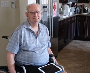 Portrait of senior man sitting on wheelchair at home