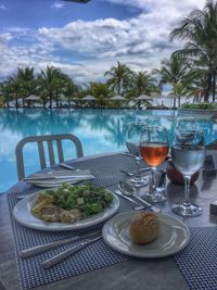 Food on table by palm trees against sky