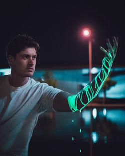 Young man standing in illuminated lights at night