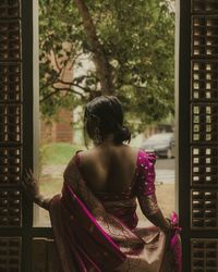 Rear view of woman looking through window