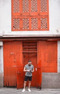 Full length of man standing against door of building