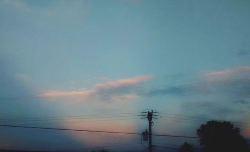 Low angle view of electricity pylon against cloudy sky