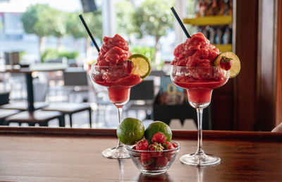 A pair of freshly made frozen strawberry daquiri cocktails on a wooden counter