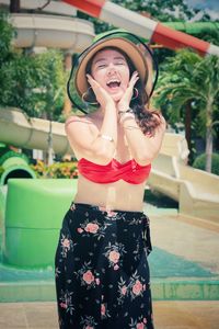 Pretty lady wearing a hat excited happy expression hands on face red bikini swimwear summer outfit