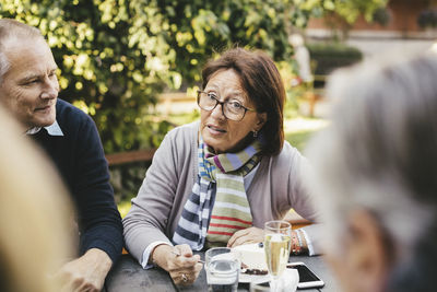 Senior woman talking with friends at cafe table