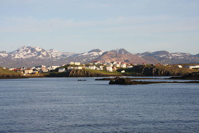 Scenic view of sea by snowcapped mountains against sky