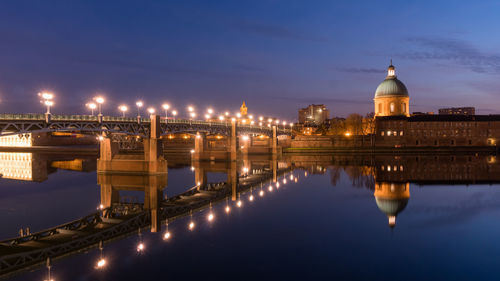 Illuminated bridge over river against sky in city at night