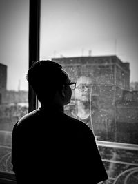 Rear view of man looking through window