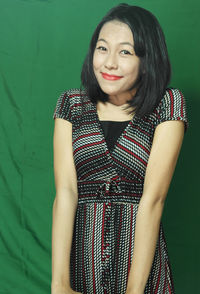 Portrait of smiling woman standing against wall