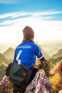 Rear view of man looking at mountain against sky