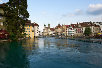 Buildings by river against sky in city