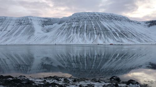 Scenic view of frozen lake by snowcapped mountains against sky