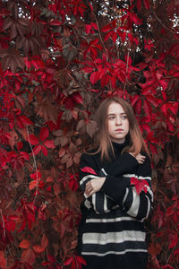 Portrait of young woman standing against plants