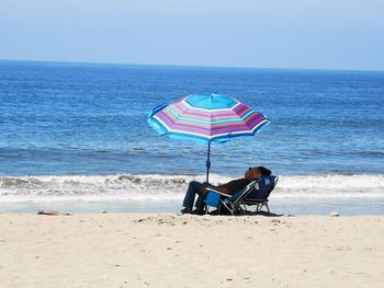 Rear view of people sitting on beach