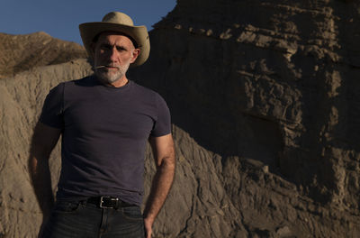 Adult man in cowboy hat on desert against mountain. almeria, spain