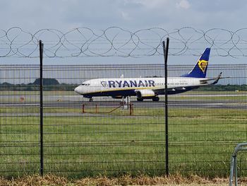 Airplane on field seen through chainlink fence