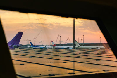 Sailboats moored in sea against sky during sunset