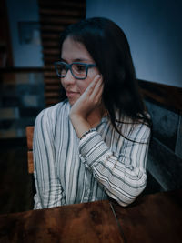 Young woman looking away while sitting on table