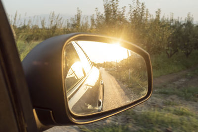 Close-up of side-view mirror at sunset